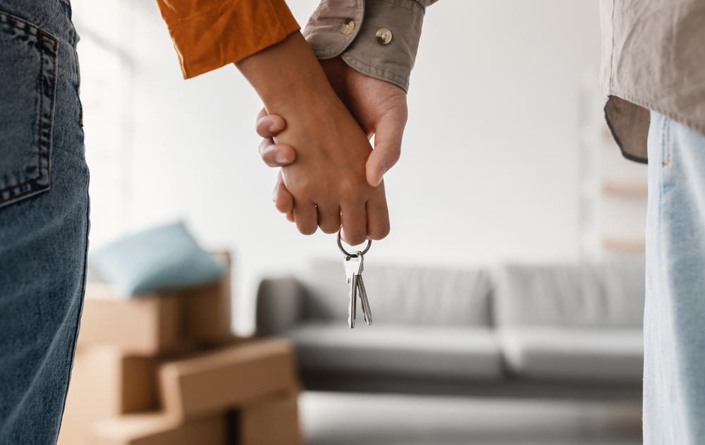 couple holding hands and new house key